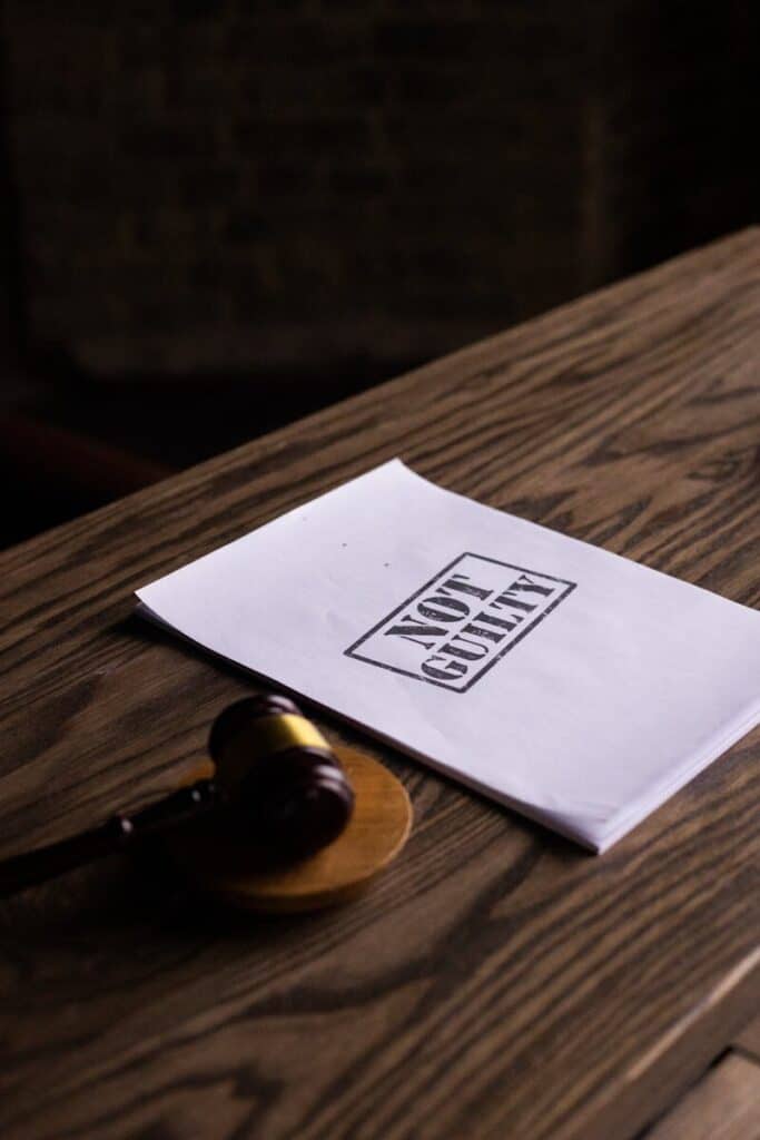 A legal gavel next to a 'Not Guilty' document on a wooden table, symbolizing justice.