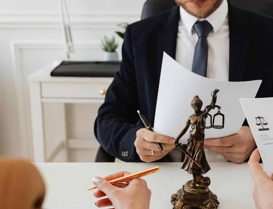 Legal professionals reviewing divorce documents in a law office with a Lady Justice statue.